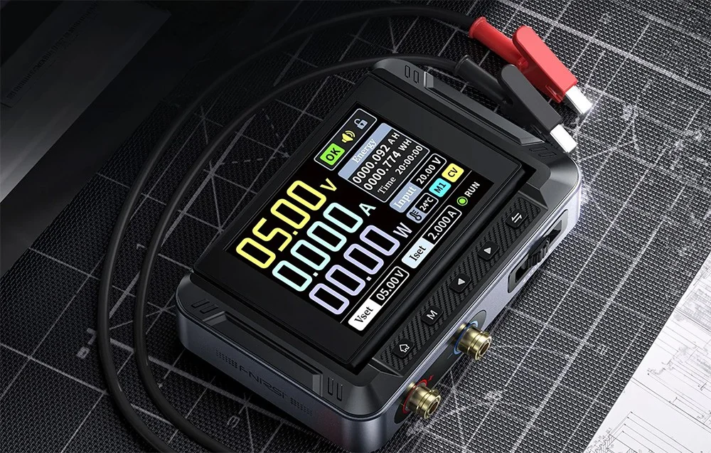 Digital power supply with a 5.00 V display screen, black wires, and alligator clips on a workbench mat.