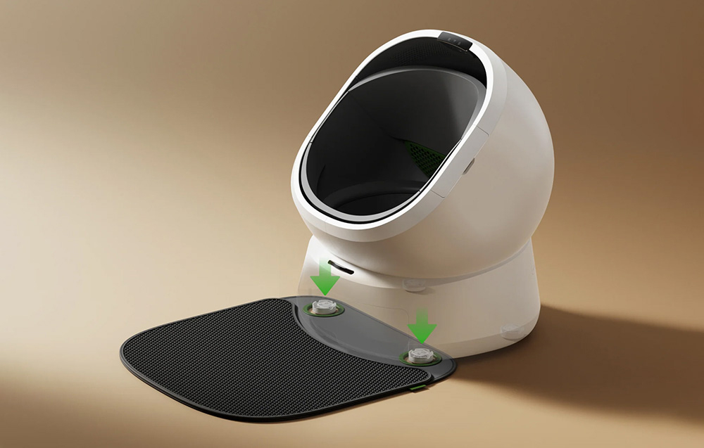 White, automatic litter box with a black mat attached to the front, marked with green arrows