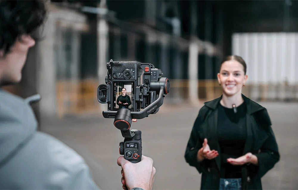 A boy holding a camera on a gimbal and recording a girl