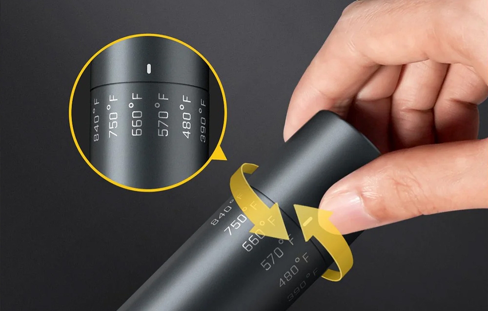 Close-up of a hand turning the knob of the black soldering iron with the temperatures marked in degrees Fahrenheit.