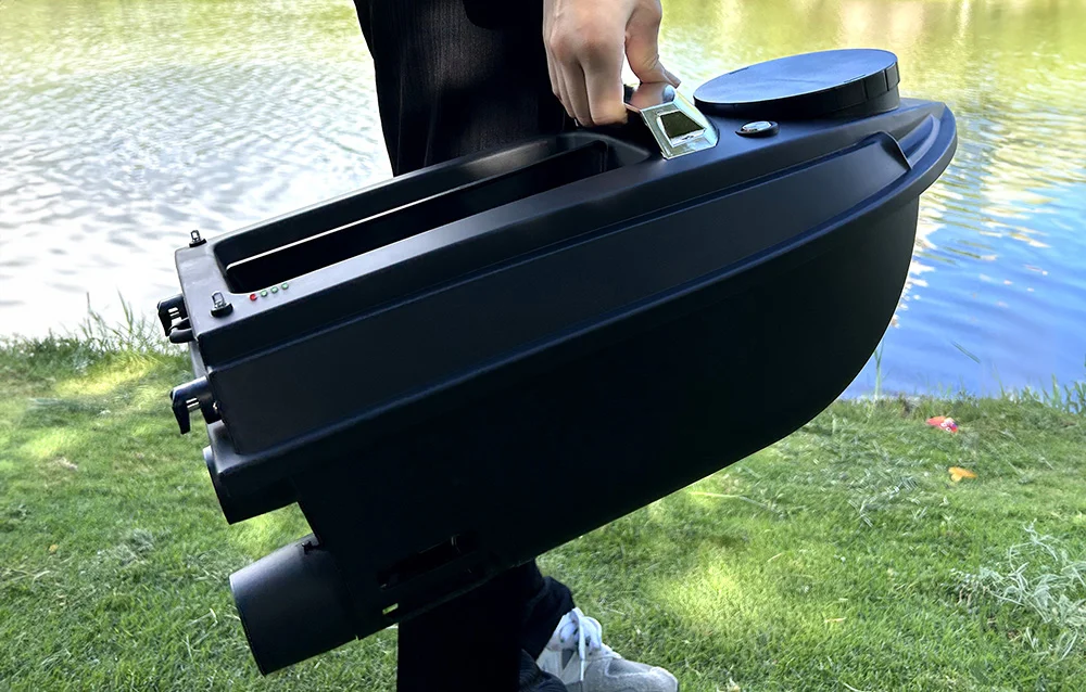 A black bait boat held in the hand