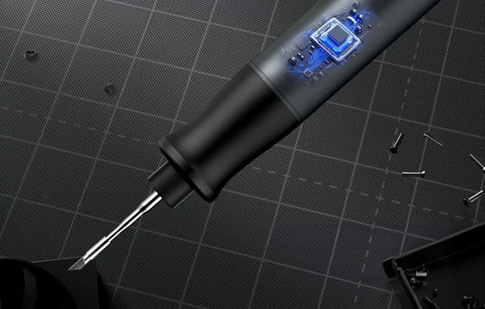 A black soldering iron with a narrow tip lying on a work mat next to small screws.