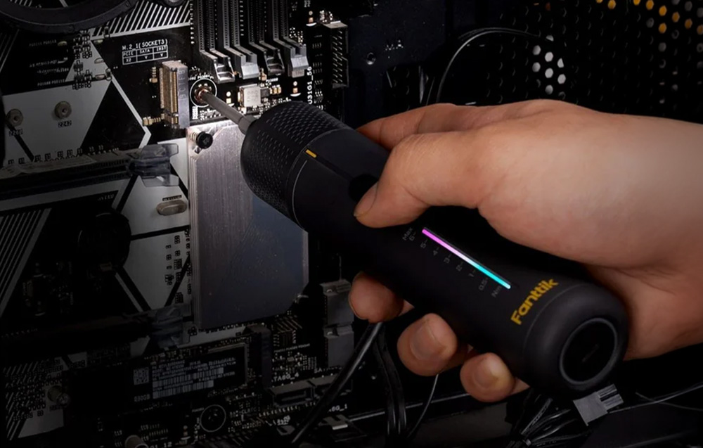 Precisely tightening a screw on a computer motherboard using a black screwdriver with a light