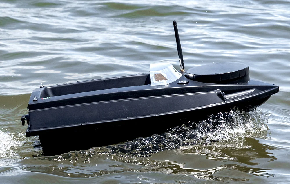 A black bait boat with white accents and an antenna moving across the water, creating waves