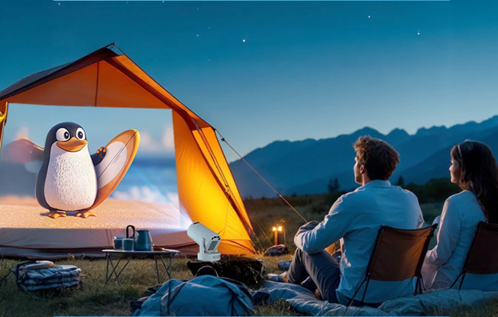 A couple sits on lounge chairs in front of a tent at night, watching an animated film featuring a penguin projected by the projector