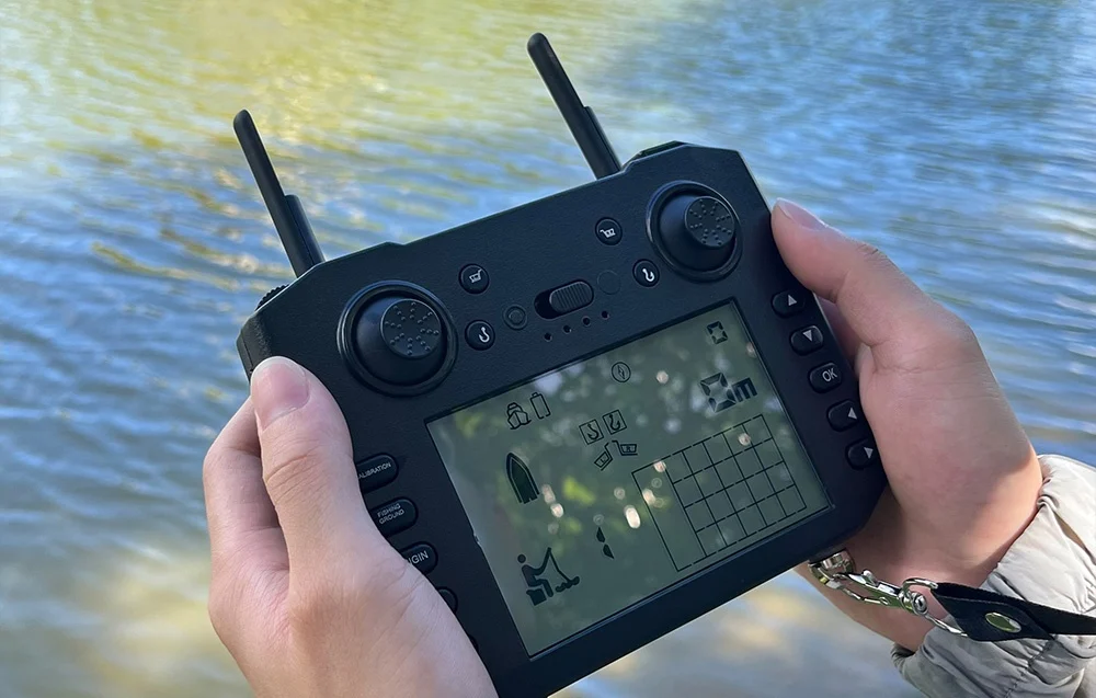 Hands holding a remote control with an LCD display showing the boat, range, and parameters above the lake’s surface