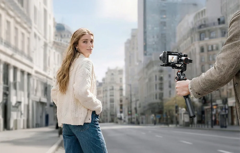 A person with a gimbal and camera recording a girl on a city street