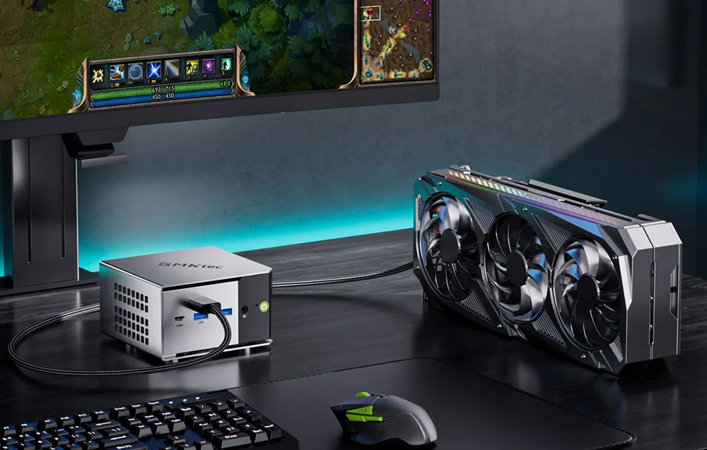 Mini PC connected via an Oculink cable to an external graphics card (eGPU) on a gamer's desk, next to a monitor and keyboard.
