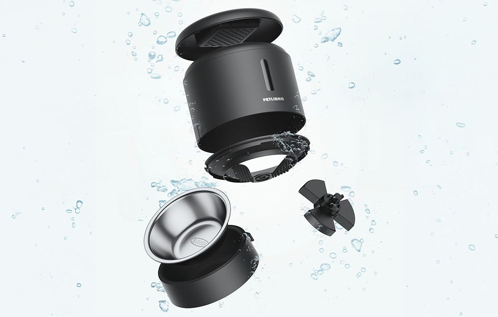 Disassembled parts of the black automatic feeder and metal bowl shown against a background with water droplets