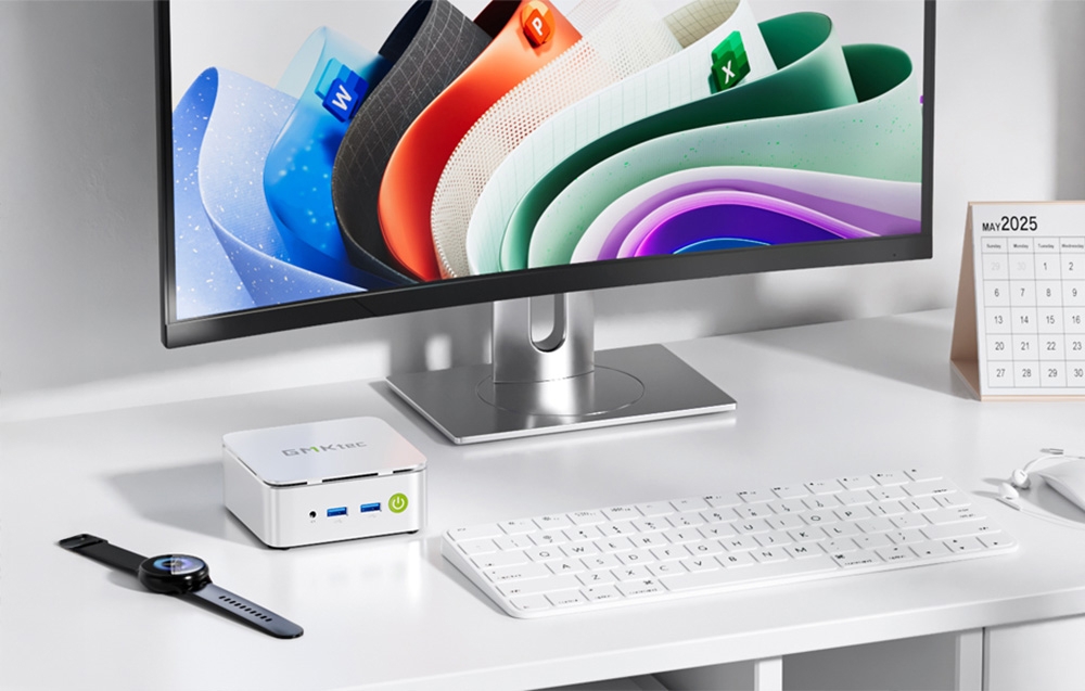 Mini PC lies on the desk next to the monitor, smartwatch and keyboard.