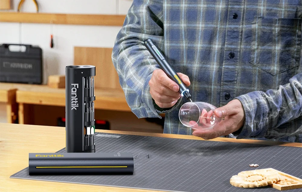 A man engraves a wine glass held in his hand.
