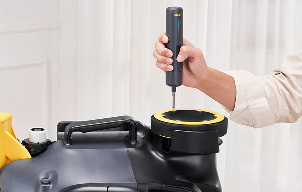 Screwing together the black housing of an electronic device using a screwdriver with a visible torque indicator