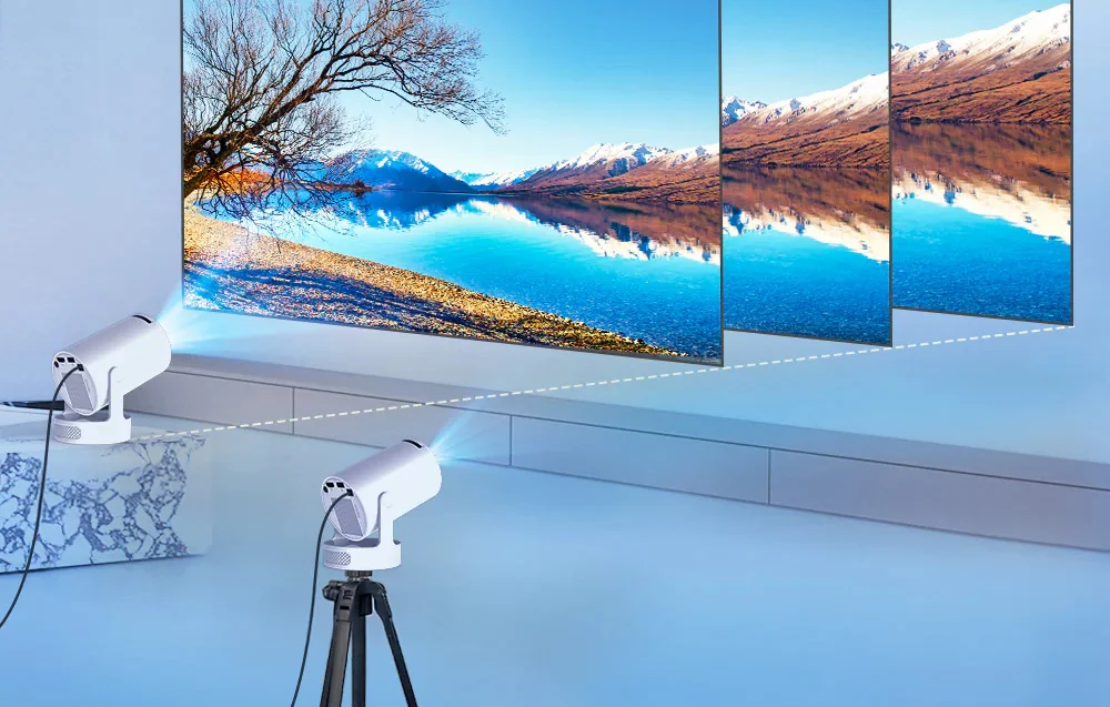 Two white projectors, one on a tripod and the other on a platform, project a panoramic image of a mountain lake onto a wide wall