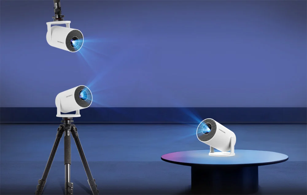 Three identical white projectors shown in various mounting configurations: suspended from the ceiling, on a tripod, and standing on a low table