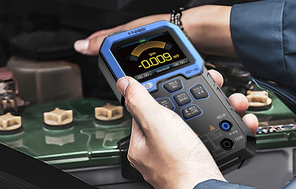 Hands holding a multimeter while measuring voltage in monitor mode above electronic components