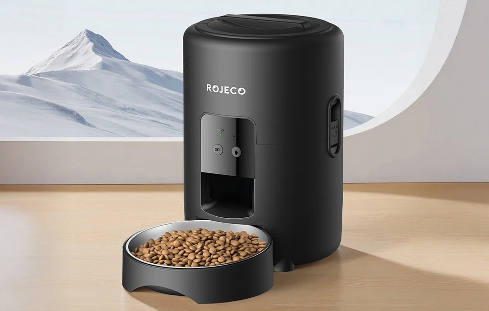 Black automatic food dispenser with a full bowl on the background of a mountainous landscape